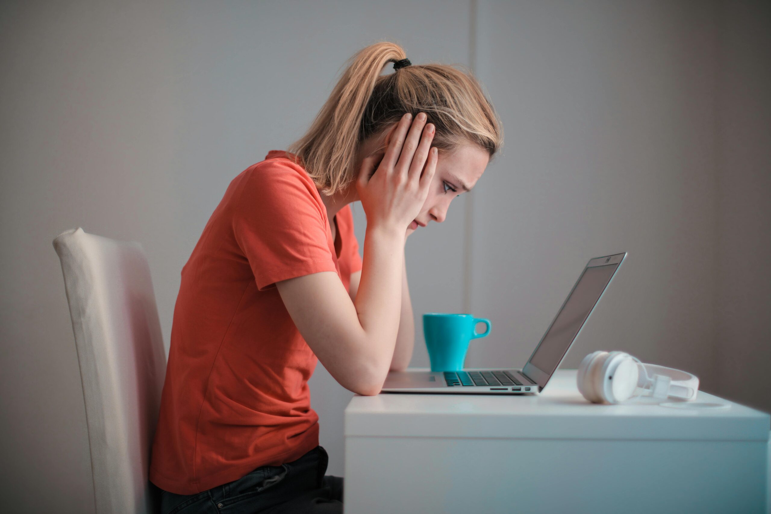 Image: woman leaning over laptop looking stressed